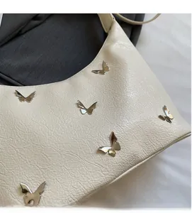 Détail du sac en cuir texturé blanc crème avec ornements papillons métalliques
