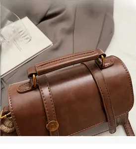 Close-up of vintage brown leather handbag featuring thick stitching and golden metal clasp