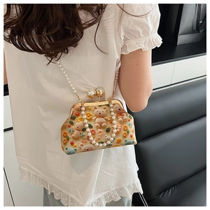 Detailed close-up of a vintage shell bag with 3D teddy bears, floral embroidery and pearl chain