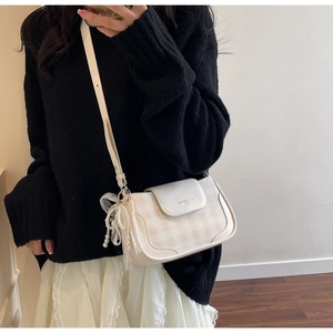 Detail of checkered square shoulder bag with pearl chain and lace bow decoration
