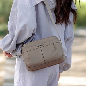 Detail of khaki nylon crossbody bag featuring ruched texture and adjustable wide strap