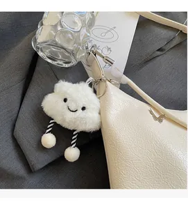 Gros plan d'un charme de nuage en peluche avec des jambes rayées sur un sac à main chic