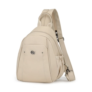 Detail of cream Oxford fabric backpack showing metal logo and water-resistant texture