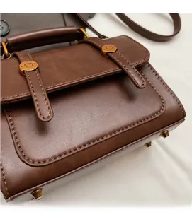 Close-up of vintage dark brown faux leather handbag with metal buckle and logo detail
