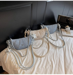 Close-up of crescent pleated crossbody bags with silver chain and star charms