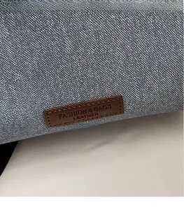 Detail of blue denim fabric with a brown leather logo patch embossed with fashion text