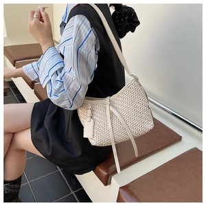 Dettaglio della trama intrecciata beige e della tracolla in pelle di questa borsa minimal