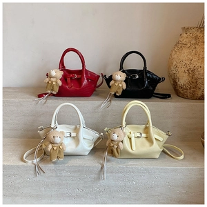 Detail of four crocodile pattern crossbody bags with plush bear charms on display