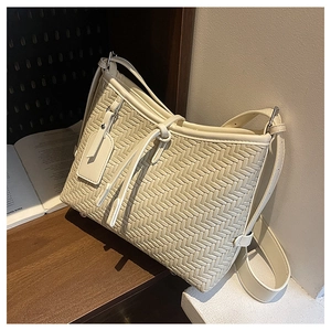 Detailed view of the V-shape leather weaving texture and detachable tag on this beige tote