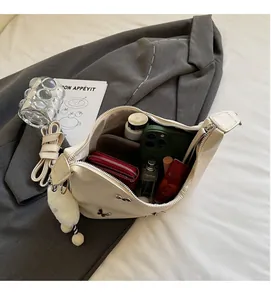 Détail montrant l'intérieur spacieux du sac papillon crème avec des essentiels