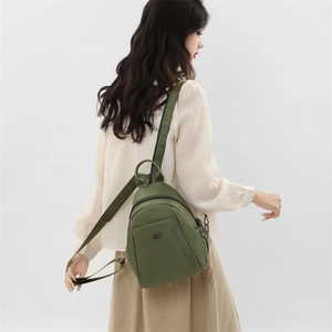 Rear view of olive green Oxford fabric backpack shown worn by a model on white background