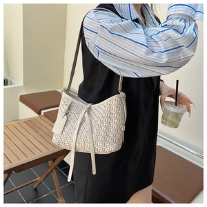 Dettaglio di una borsa hobo intrecciata beige con trama fine e lunghi accenti di nappe