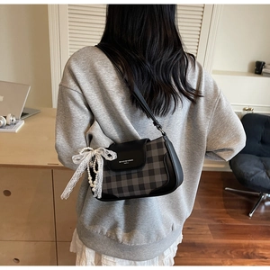 Detail of checkered shoulder bag with lace bow and pearl pendant on back view model