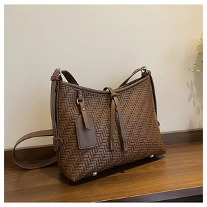 Detailaufnahme der dunkelbraunen geflochtenen Ledertasche mit silbernen Metallschutzfüßen