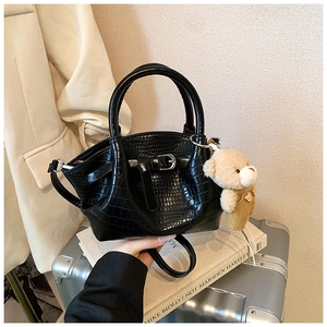 Detail of black crocodile embossed bucket bag with silver buckle and plush bear charm
