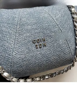 Close-up of blue denim texture with silver metal logo and V-shaped decorative stitching