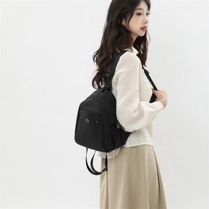 Detail view of water-resistant black Oxford backpack with multi-layer zipper and metal logo