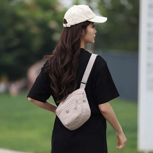 Detail of beige nylon crossbody bag with multi-zipper compartments and adjustable strap