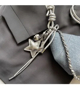 Detail of silver star charm and heart pendant on a blue denim shoulder handbag