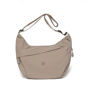 Detail view of khaki nylon crescent bag featuring adjustable strap and circular logo