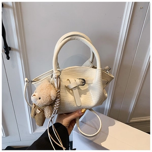 Close-up of cream crocodile pattern handbag with cute bear charm and buckle detail