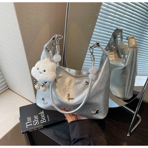 Détails du sac hobo argenté avec écussons papillons et breloque en forme de nuage blanc