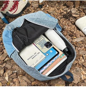 Blue denim backpack interior showing ample storage for tablets, notebooks and a water bottle