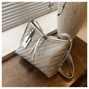 Detail of silver metallic woven texture on leather crossbody bag with metal feet