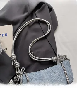 Detail of light blue denim croissant bag with diagonal quilting and silver chain strap