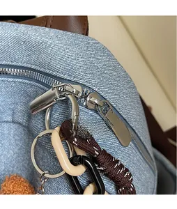 Detailed macro view of denim backpack zipper with polished silver hardware and charms