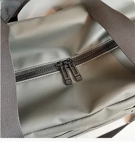 Dettaglio delle doppie cerniere in metallo e del manico intrecciato della borsa da viaggio