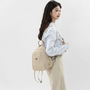 Side view of beige nylon backpack on model showing large capacity and side pockets