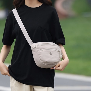 Detail of light taupe nylon crossbody bag with front zip pocket and adjustable strap
