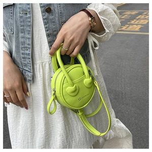 Detail of neon green mini round handbag with heart-shaped handle joints and fashion text