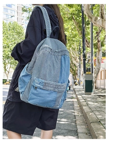 Detail of denim patchwork backpack showing blue fabric texture in outdoor street setting