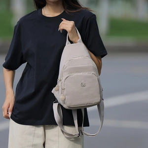 Detail of adjustable strap and nylon texture on beige crossbody bag worn outdoors