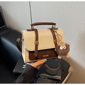 Detail of two-tone crossbody bag with round handle and cute brown plush monster charm
