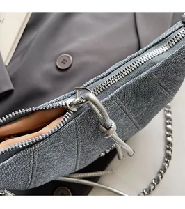 Detailed close-up of the silver zipper and denim texture on this blue crossbody bag