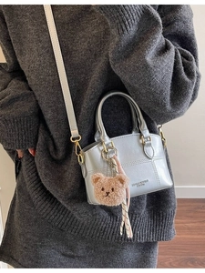 Silver metallic bucket crossbody bag for women featuring a plush bear charm and handle
