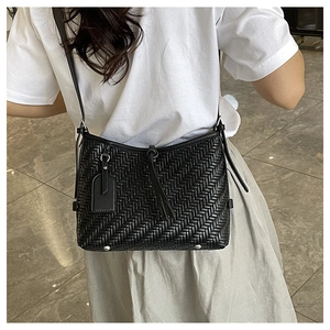 Close-up of black woven leather shoulder bag with fringe tassel and protective studs