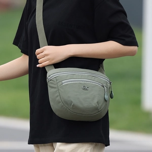 Macro detail of olive green nylon saddle bag with metal logo and zipper compartments
