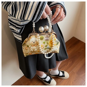 Detail of vintage beige shell bag featuring a 3D woven bear pattern and pearl handle