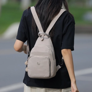 Close-up of beige Oxford cloth crossbody bag with metal logo detail and smooth texture