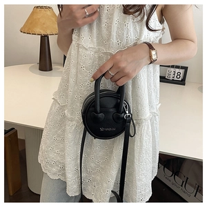 Detail view of mini round crossbody bag with heart accents and lychee grain texture
