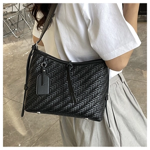 Close-up of black woven leather texture with protective silver feet on a large tote bag