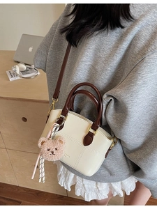 Chic beige crossbody bucket bag with brown handles and a cute plush bear charm