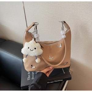 Détail du sac à main camel en similicuir avec papillons argentés et pendentif peluche