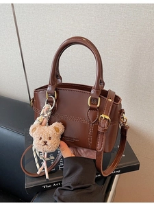 Dark brown leather bucket bag with cylinder handles and cute plush bear charm