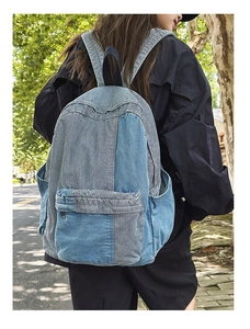 Outdoor street view of a model wearing a patchwork denim backpack in shades of blue