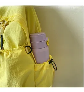 Water-resistant yellow backpack side pocket detail with drawstring and purple water bottle